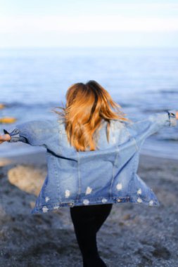 Çekici kız sahil boyunca yürür ve neşeyle kum üzerinde aptallar