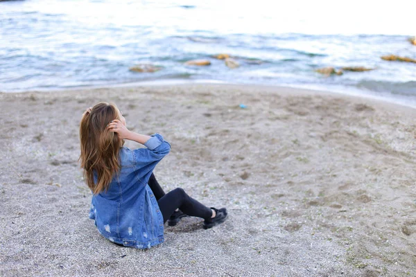Hermosa chica descansando, sentada junto al mar y posando en cámara en b — Foto de Stock