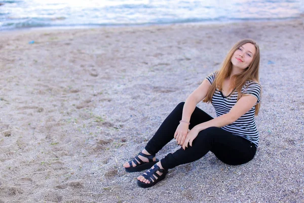 Una donna premurosa guarda il paesaggio marino e ascolta il surf, seduta — Foto Stock