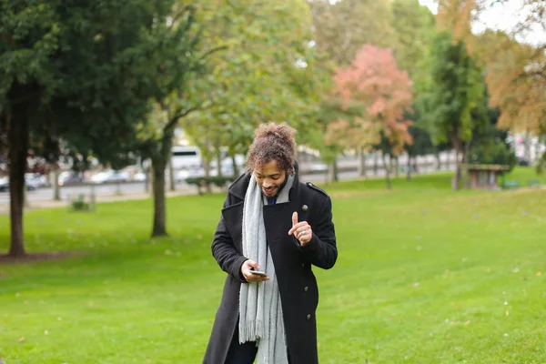 Spanyol férfi barátnője a smartphone-ban park beszélgetni. — Stock Fotó