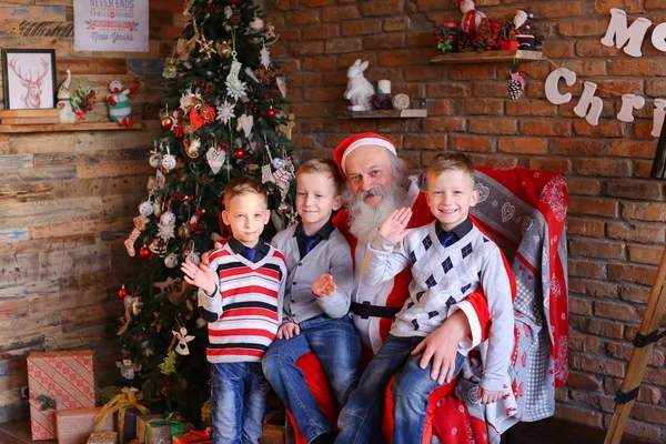 Drei junge Jungen erzählen Weihnachtsmann lustige Geschichten in dekoriert in — Stockfoto