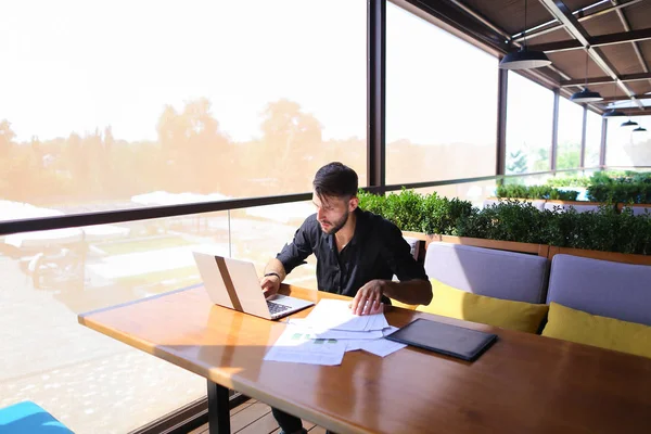 Copywriter typing text on laptop at cafe table.