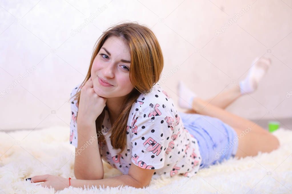 Charming girl  smiling and posing, lying on carpet on floor in b