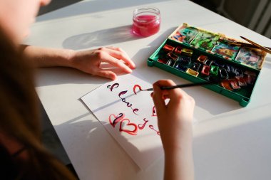 Kadın sanatçı italik italik yazıt kağıt s üzerinde yazıyor.