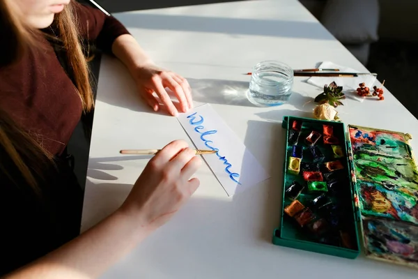 Jeune femme peintre écrit aquarelle écriture sur papier, assis — Photo