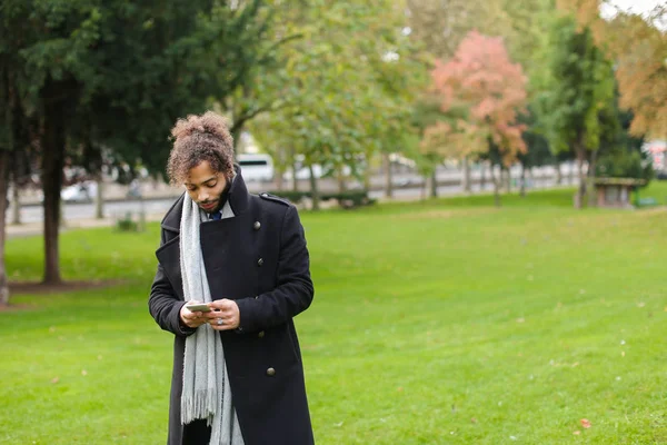 Spanischer Mann chattet mit Freundin auf Smartphone im Park. — Stockfoto