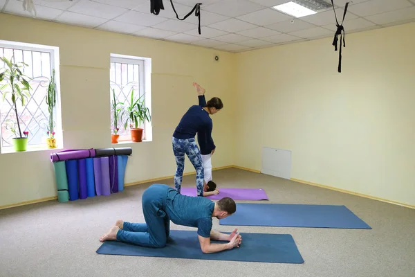 Young woman yoga trainer teaches the boy and girl to do the exer