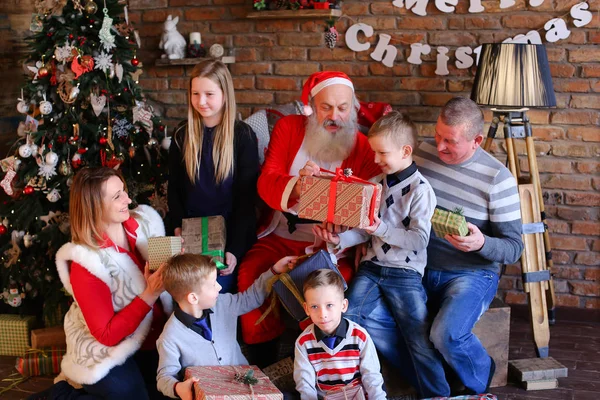 Papai Noel dá presentes de Ano Novo à grande família no quarto decorado — Fotografia de Stock