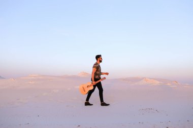 Dese aracılığıyla elinde gitar ile görkemli Müslüman genç adam yürüyor