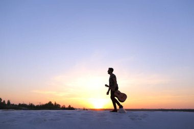 Görkemli Arap adam elinde gitar ile kumlu des Hill'de yürür