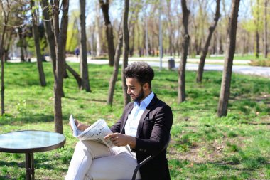 Melez adam caf ve gülümsüyor gazete okuma.