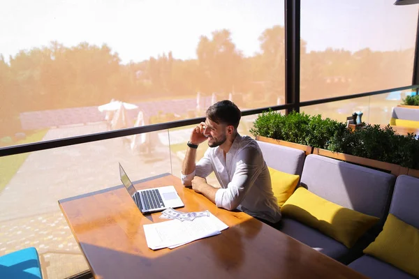 Vastgoedmakelaar praten door smartphone en werken met laptop — Stockfoto