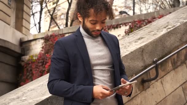 Guapo medio nigeriano niño quedarse con la tableta y ver en el reloj . — Vídeos de Stock