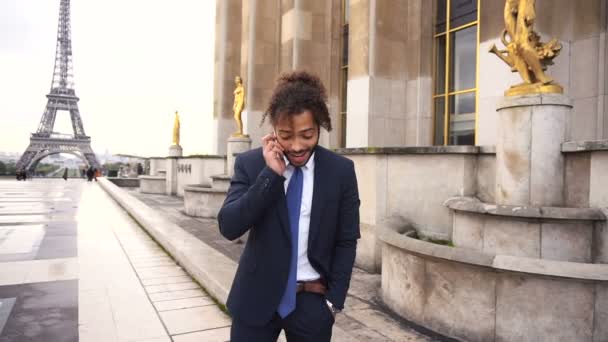 Mulato falando com a namorada por telefone perto da Torre Eiffel em câmera lenta . — Vídeo de Stock