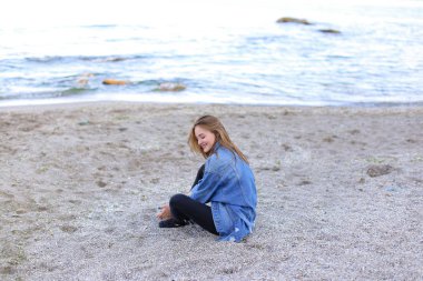 Dinlenme, deniz kenarında oturan ve b kameraya poz güzel kız