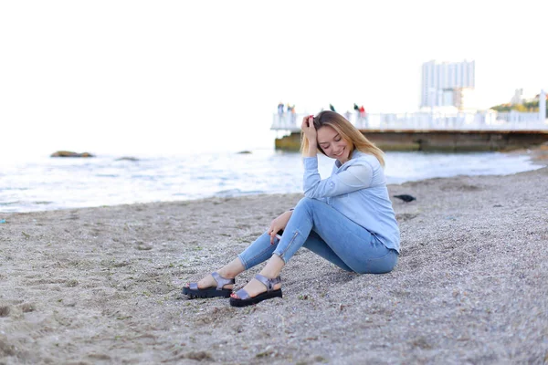 Leende ung kvinna vilar på stranden och poserar i kameran, sitter — Stockfoto