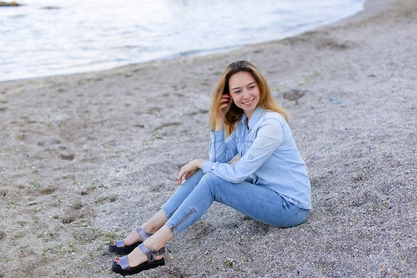 Sonriente joven descansa en la playa y posa en la cámara, sentado —  Fotos de Stock