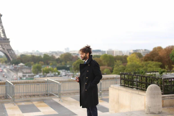 Arabian boy walking near Eiffel Tower with smartphone in slow mo