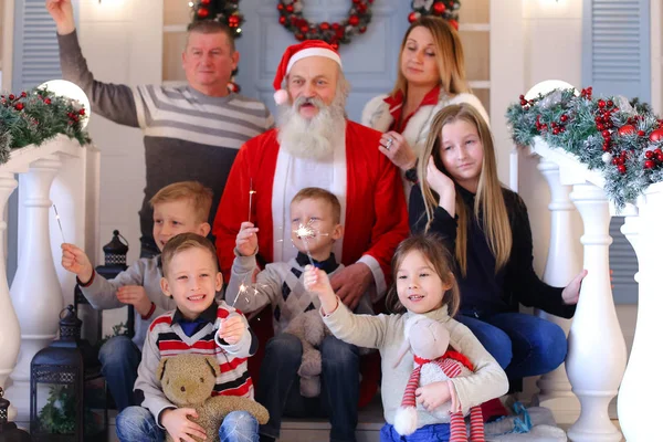 Friendly family and Santa Claus posing for camera on the porch of ho — стоковое фото