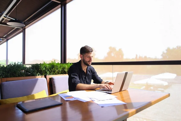 Caposquadra di successo utilizzando laptop e documenti al caffè . — Foto Stock