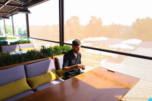 Hombre próspero utilizando el teléfono inteligente para la conversación un banco de energía un — Foto de Stock