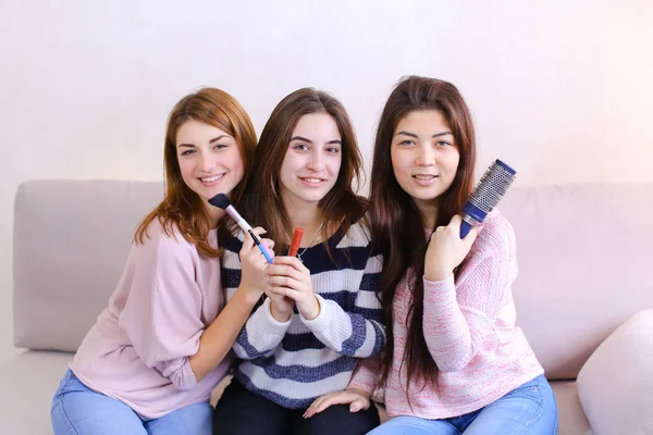 Drie aantrekkelijke jonge vrienden poseren met een glimlach op camera en — Stockfoto
