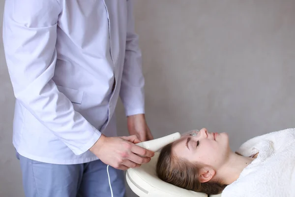 Cosmetologist guy makes special face massage to girl with cosmet — Stock Photo, Image