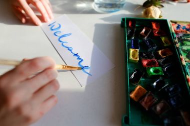 Genç kadın ressam suluboya yazma oturan kağıt üzerinde yazıyor.