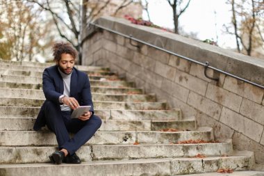 Yakışıklı yarım Nijeryalı adam adımları tablete tarafından kızla sohbet