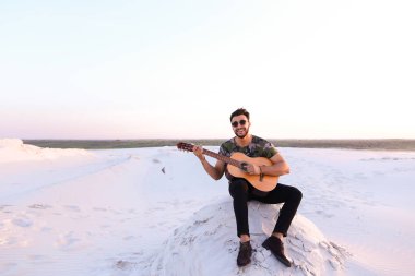 Sevimli genç erkek Arap ses gitar, Hill'de oturan sahiptir