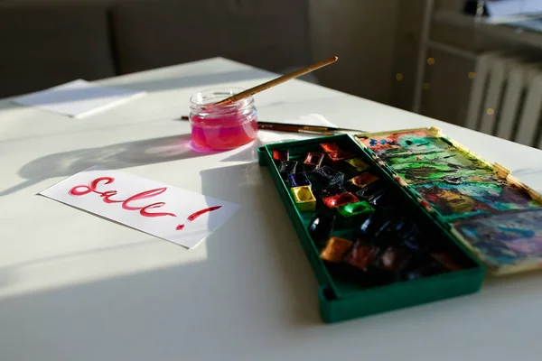 Inscrição aquarela Venda em folha branca de papel, na mesa em — Fotografia de Stock