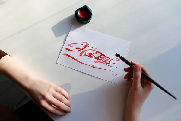 Female artist paints bright inscription on paper sheet with ink — Stock Photo, Image