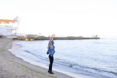 Çekici kız sahil boyunca yürür ve neşeyle kum üzerinde aptallar