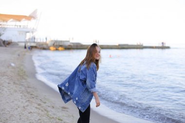 Çekici kız sahil boyunca yürür ve neşeyle kum üzerinde aptallar