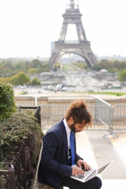 S arka planda Eyfel Kulesi ile dizüstü bilgisayar kullanarak seyahat Yöneticisi