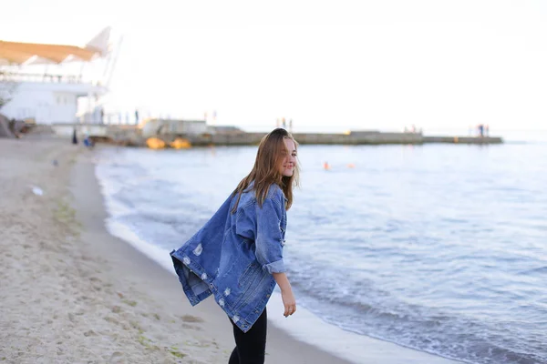 Chica encantadora camina a lo largo de la costa y tontos alegremente alrededor en la arena —  Fotos de Stock