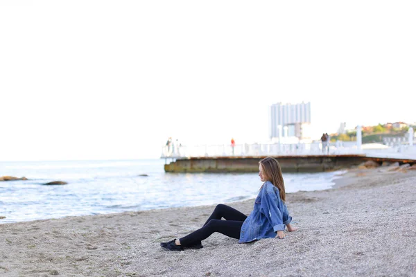 Hermosa joven mujer se relaja sentada en la playa y disfruta de la vista o — Foto de Stock