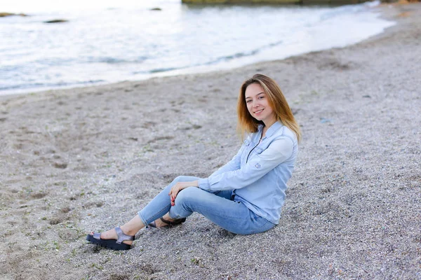 Sonriente joven descansa en la playa y posa en la cámara, sentado —  Fotos de Stock