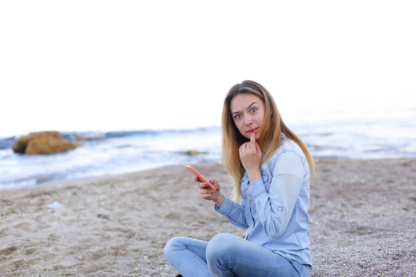 Güzel kız gülümseme ile telefonda sohbet eden ve plaj n üzerinde oturur — Stok fotoğraf
