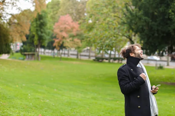 Hombre hispano charlando con su novia en un smartphone en el parque . — Foto de Stock