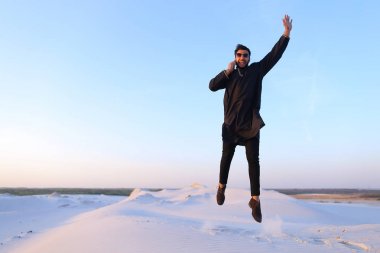 Neşeli Arap adam telefonla iletişim kurar ve m satırda sekerek