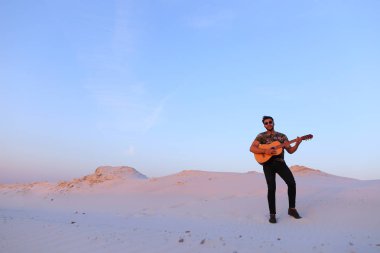 Arap adam çöl güzelliği ile ilham gider ve gitar çi çalış