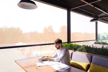 Amerikalı yatırımcı laptop ve diyagram belgelerle çalışma