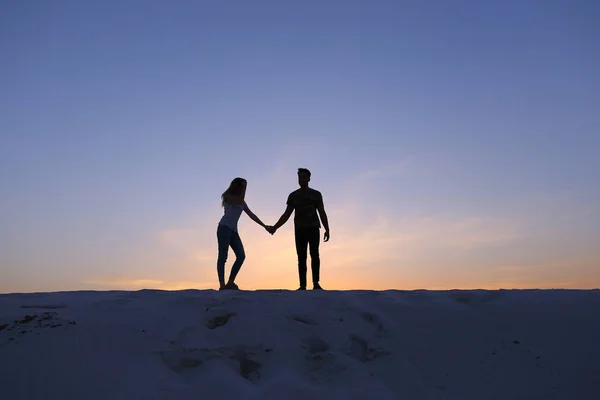 Os amantes seguram uns aos outros braços e rodopiam na colina arenosa no deserto em — Fotografia de Stock