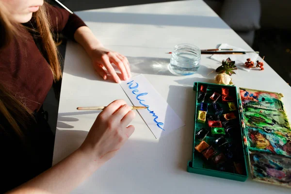 Pelukis wanita muda menulis cat air menulis di atas kertas, duduk — Stok Foto