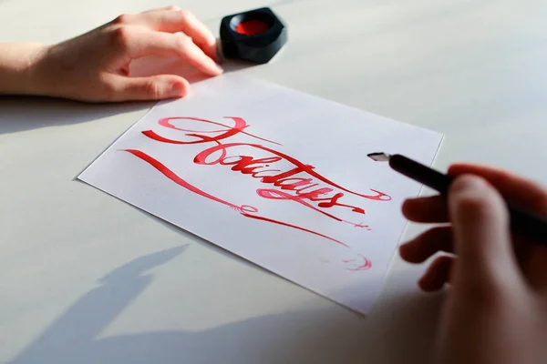 Женщина-художник рисует яркую надпись на бумажном листе чернилами — стоковое фото