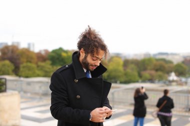 Melez işadamı smartphone cep telefonu ile Eife yakınındaki ortağıyla konuşmak