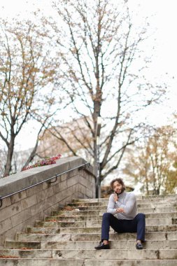 Smartphone tarafından arama ve üzerinde sigara yakışıklı yarı Amerikalı adam