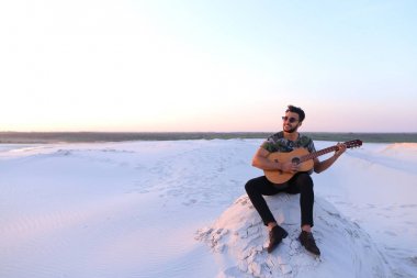 Sevimli genç erkek Arap ses gitar, Hill'de oturan sahiptir