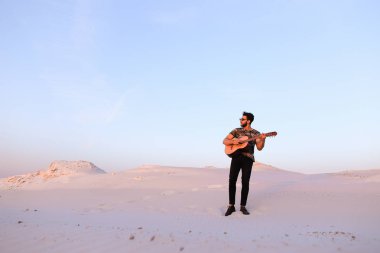 Arap adam çöl güzelliği ile ilham gider ve gitar çi çalış